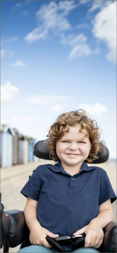 Image d’un jeune garçon souriant en fauteuil roulant sur une plage